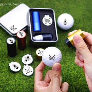 Puede incluir: Un juego de golf con un sello personalizado, marcadores de bolas de golf y un kit de sellos. El kit incluye un cartucho de tinta azul, un cartucho de tinta negra y un sello dorado. Las bolas y marcadores tienen texto personalizado.