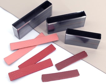 May include: Three rectangular leather punch tools with black handles and silver blades. Five leather strips in various shades of pink and red.