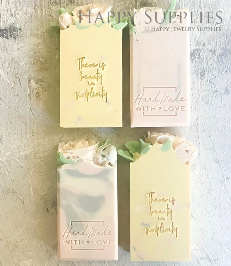 May include: Four handmade soap bars with floral embellishments. Two bars feature the text "There is beauty in simplicity" and the other two bars feature the text "Hand Made with Love".