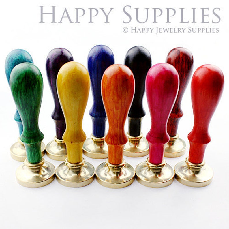 May include: A set of ten colorful wooden wax seal stamps with brass bases. The stamps are arranged in a row, with the handles facing the viewer. The colors of the stamps are red, orange, yellow, green, blue, purple, black, brown, and white.