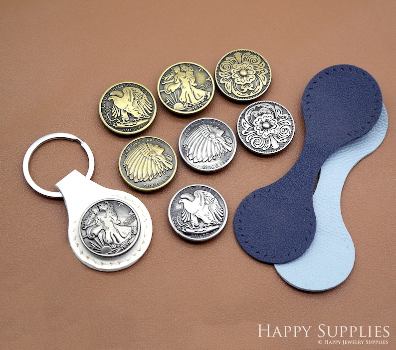 May include: Assortment of metal buttons with various designs, including a bald eagle, a Native American headdress, and floral patterns. The buttons are displayed on a brown surface with a blue and light blue leather strap.
