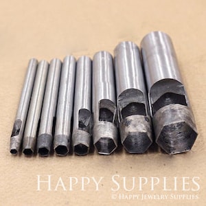 May include: A set of nine silver metal hole punches with hexagonal shapes. The punches are arranged in order of size, with the smallest on the left and the largest on the right.