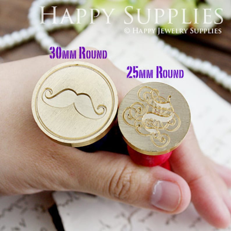 2 wax sealing stamps are hold by a hand. They are  25mm and 30 mm size.