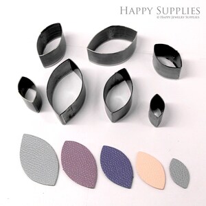 May include: Set of eight metal leaf-shaped leather craft punches in various sizes, along with six leather pieces cut with the punches in gray, purple, blue, and peach.