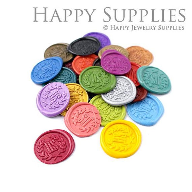 May include: Assortment of colorful wax seals with a gold "IHS" design and a laurel wreath. The seals are arranged in a pile on a white background.