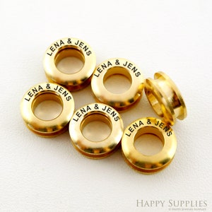 May include: Five gold-colored metal eyelets with the text "LENA & JENS" engraved around the outside of each eyelet.