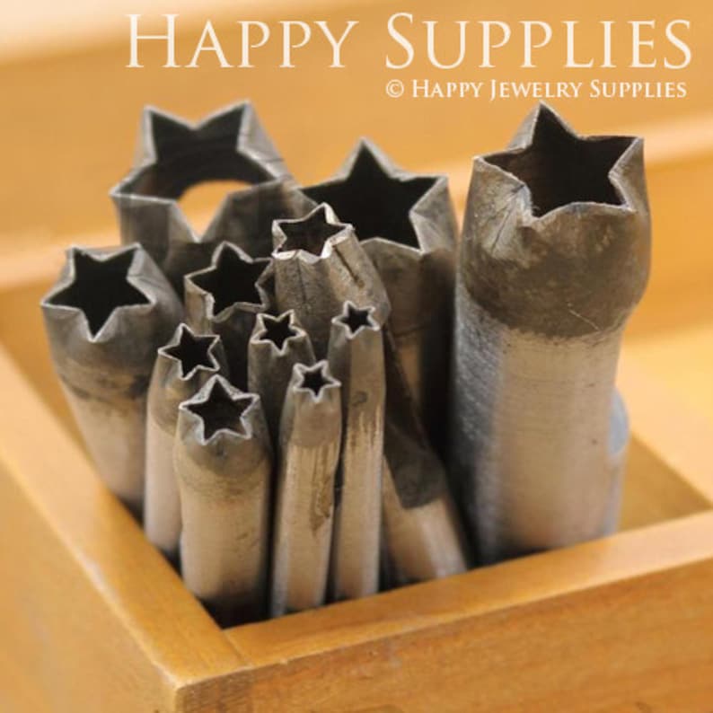 May include: A set of metal star-shaped punches in a wooden box. The punches are used for crafting jewelry and other projects.