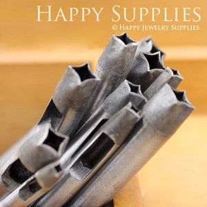 May include: A set of metal star-shaped hole punches. The punches are arranged in a pile, with the star-shaped holes facing up. The punches are made of a silver-colored metal and have a smooth, polished finish.