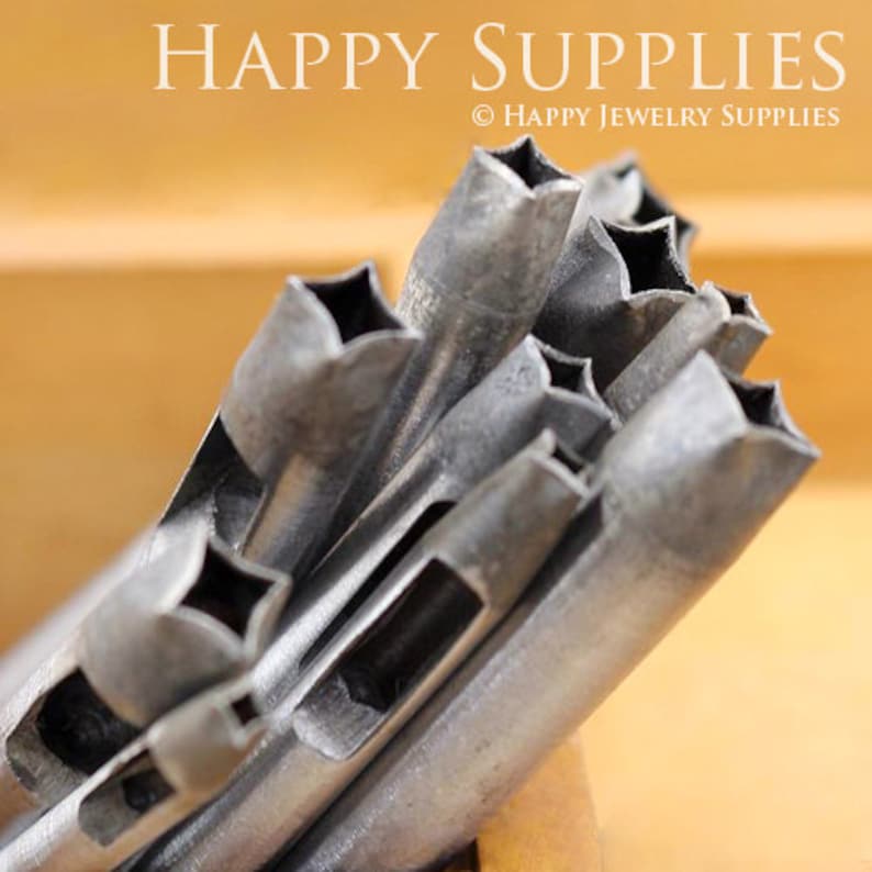 May include: A set of metal star-shaped hole punches. The punches are arranged in a pile, with the star-shaped holes facing up. The punches are made of a silver-colored metal and have a smooth, polished finish.