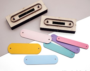 May include: Wooden die-cut tools with metal outlines and a variety of colorful leather tags. The tags are in shades of yellow, blue, pink, purple, and teal. Each tag has two pre-punched holes.