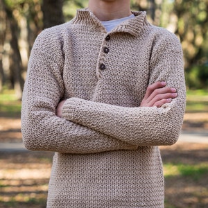 May include: A beige crocheted sweater with a button-up collar and a small leather patch on the bottom.