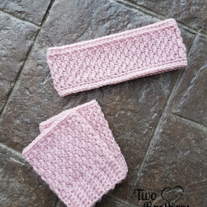 May include: Two pink crocheted headbands, one is a long headband and the other is a shorter headband. The headbands are on a brown tiled surface. The text "Two Brothers Blankets" is visible in the bottom right corner of the image.