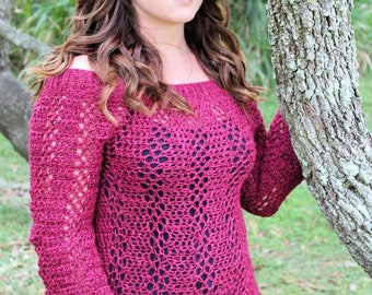 Puede incluir: Un top de crochet color granate con un delicado patrón de calado. El top tiene un escote ligeramente caído y mangas largas.