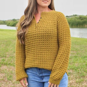 May include: A mustard yellow waffle knit sweater with a button-up neckline and long sleeves.