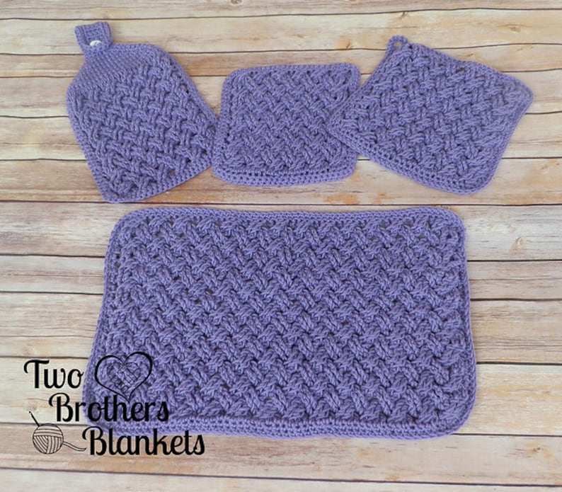 Puede incluir: Un juego de cuatro art&iacute;culos de cocina de ganchillo en tono lavanda. El conjunto incluye una toalla colgante, dos agarraderas cuadradas y un pa&ntilde;o de cocina rectangular. Los art&iacute;culos presentan un patr&oacute;n de tejido texturizado. El texto "Two Brothers Blankets" es visible.
