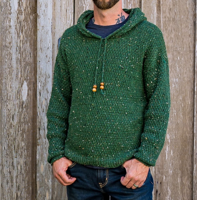 May include: A green hooded sweater with a speckled pattern. The sweater has a drawstring hood with wooden beads.