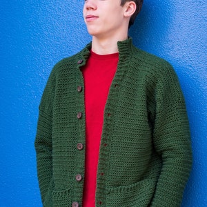 May include: A green crocheted cardigan with a red t-shirt underneath and blue jeans. The cardigan has a button closure and two pockets.