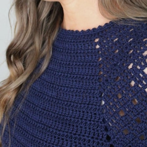 May include: A navy blue crochet sweater with a lacy design on the shoulders.