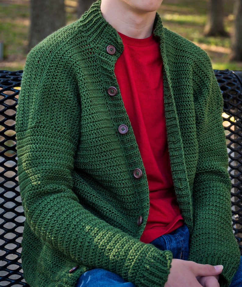 May include: A green knitted cardigan with a button-up front and long sleeves. The cardigan is made of a soft, textured yarn and has a casual, relaxed fit.