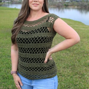 Może przedstawiać: Zielony top na szydełku o luźnym, ażurowym wzorze. Top ma okrągły dekolt i krótkie rękawy. Modelka nosi top z niebieskimi dżinsami.