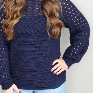 May include: A navy blue crocheted sweater with a lacy pattern on the sleeves and neckline.