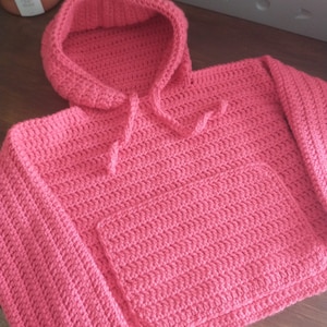 May include: A pink crocheted hooded sweater with a pocket on the front.