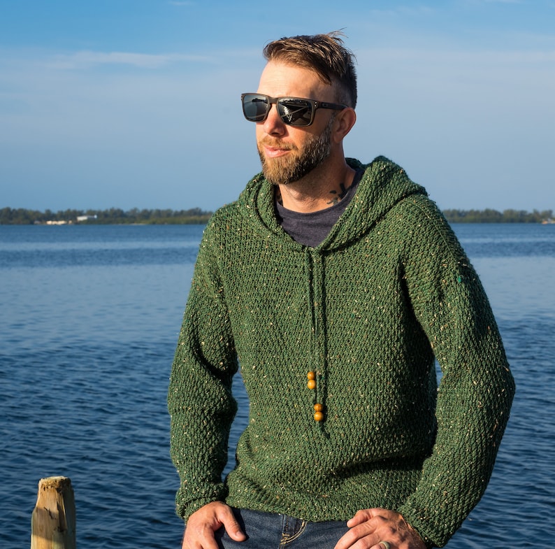 May include: A green hooded sweater with a speckled texture and wooden toggles. The sweater is made of a soft, comfortable material.