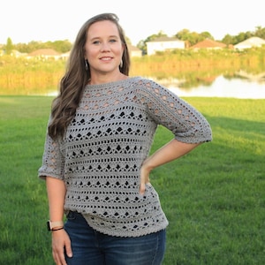 May include: A gray crochet top with a lacy pattern and three-quarter sleeves. The top is loose-fitting and has a boat neck.
