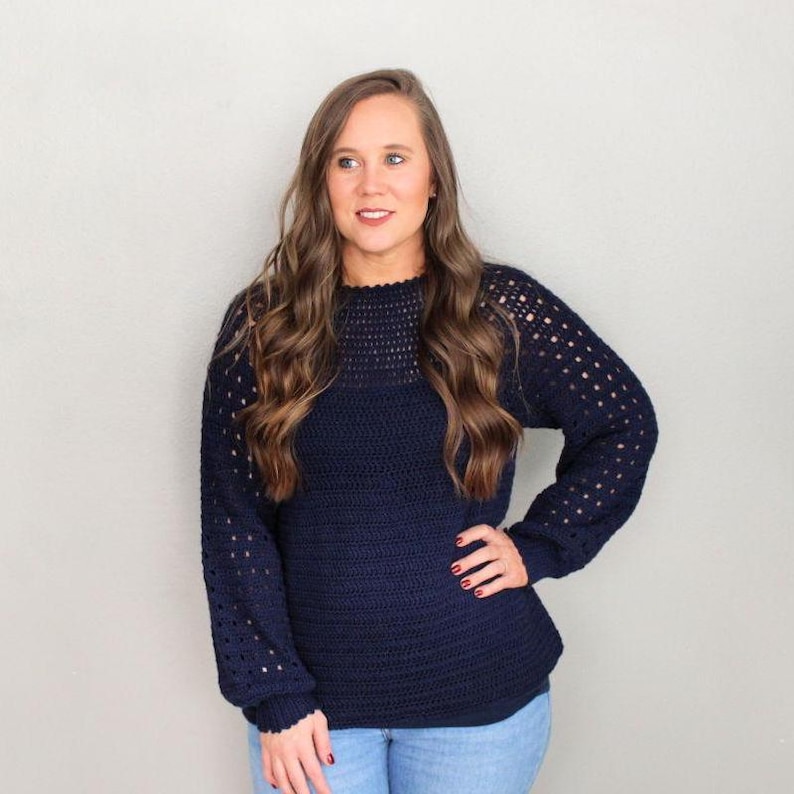 May include: A navy blue crocheted sweater with a lacy pattern on the sleeves and neckline.