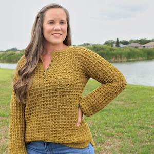 May include: A mustard yellow waffle knit sweater with a button-up neckline and long sleeves.