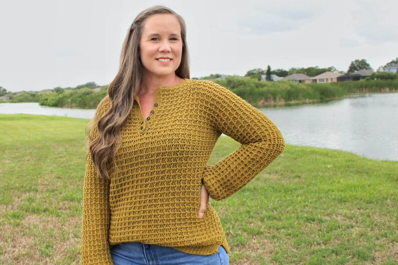 May include: A mustard yellow waffle knit sweater with a button-up neckline and long sleeves.