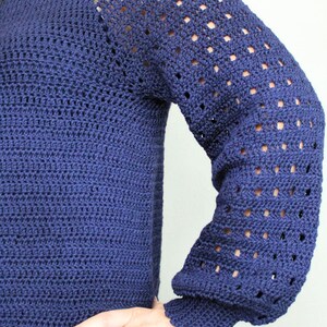 May include: A navy blue crocheted sweater with a lacy pattern on the sleeves.