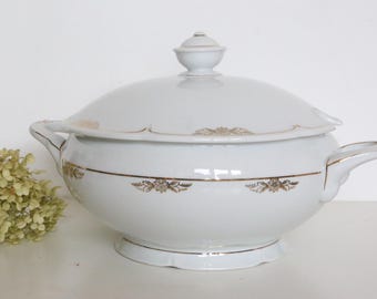 May include: White porcelain serving bowl with a lid and two handles. The bowl has a gold trim and floral design.