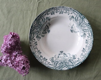 May include: A white ceramic soup bowl with a green floral design. The bowl has a wide rim and a deep well.