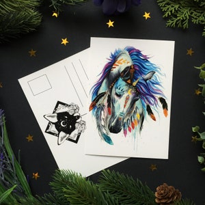 May include: A postcard featuring a watercolor illustration of two horses with tribal-inspired designs. The horses have blue and purple manes, adorned with feathers and celestial accents. A second postcard with a black and white illustration is also present.