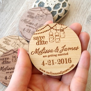 May include: Wooden save the date magnet with a rustic design. It features a string of lights with mason jars, the text "save the date", the names "Melissa & James", the text "are getting married", the date "4-21-2016", and the website "www.melissaandjames.com".