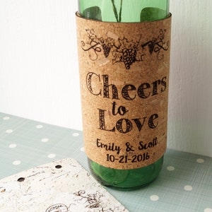 May include: A cork-wrapped wine bottle with a personalized label that reads "Cheers to Love Emily & Scott 10-21-2016".