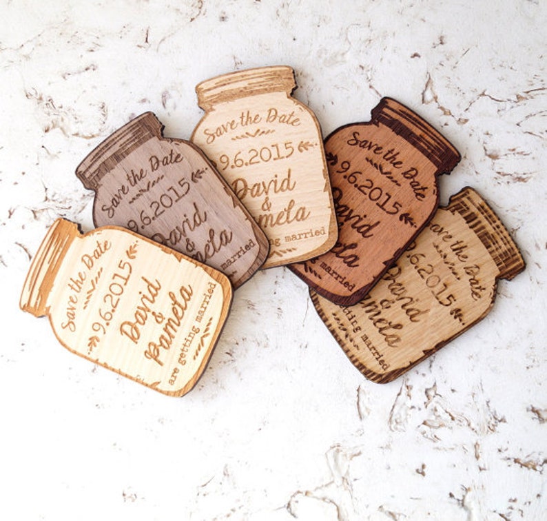 May include: Six wooden save the date magnets shaped like mason jars with the text "Save the Date" and the date "9.6.2015" and the names "David & Pamela" on each magnet.