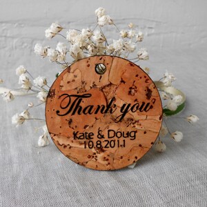 May include: Round cork thank you tag with the text "Thank you" in cursive script, followed by "Kate & Doug 10.8.2011".