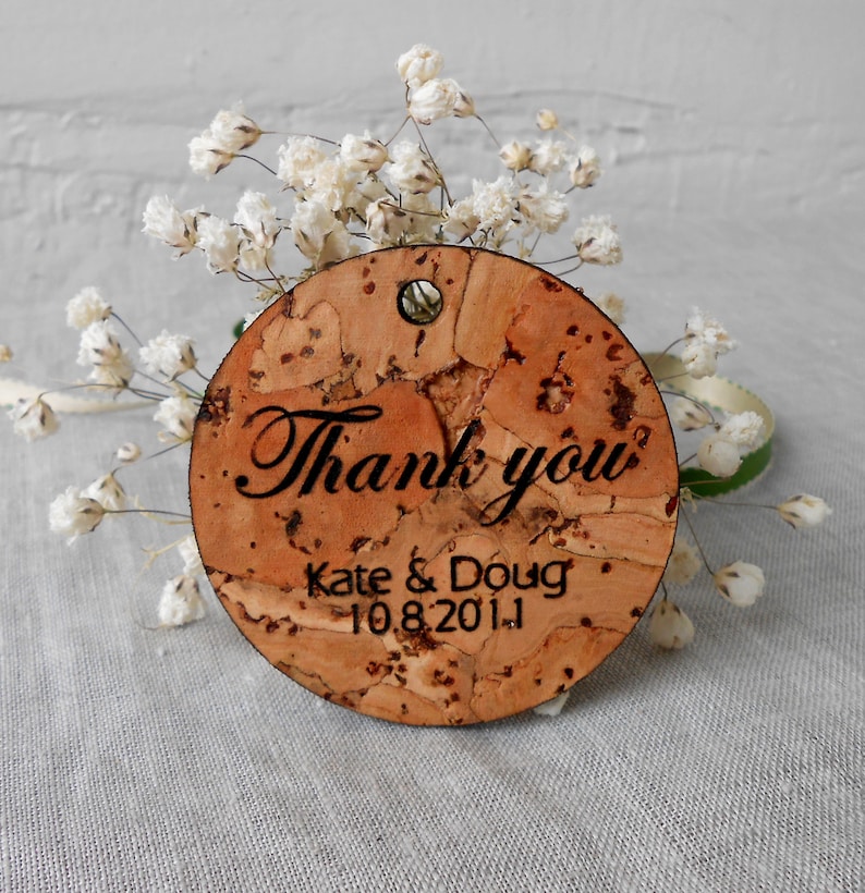May include: Round cork thank you tag with the text "Thank you" in cursive script, followed by "Kate & Doug 10.8.2011".