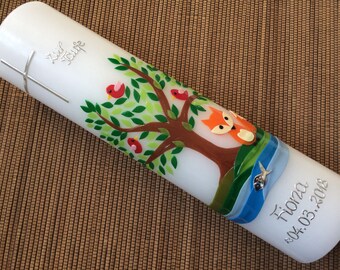 May include: White baptism candle with a silver cross and the words "Zum Taufe" on the top. The candle is decorated with a brown tree with green leaves, three red birds, and a fox. The bottom of the candle has a blue and white ribbon with a silver fish and the name "Fiona" and the date "04.03.2018".