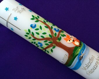 May include: White baptism candle with a blue ribbon, a tree with green leaves and blue birds, and a fox. The candle is decorated with silver stars and a cross. The text "Zur Taufe" and "Valentin Alexander" is written on the candle.