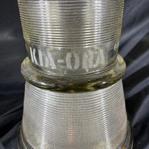 May include: A clear glass jar with a textured surface and the word "KIA-ORA" etched on the side.