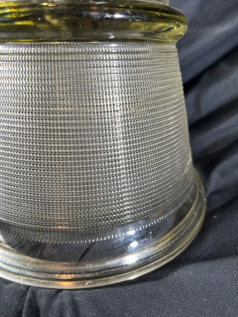 May include: A clear glass lampshade with a textured, grid-like pattern. The shade has a wide, flared base and a narrow top.