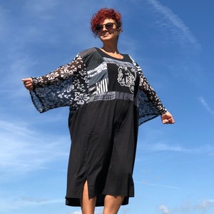 Könnte beinhalten: Eine Frau trägt einen schwarz-weißen Kimono mit floralem Muster und einen schwarzen Rock sowie eine Sonnenbrille. Der Kimono hat ein Blumenmuster und der Rock ist knielang.