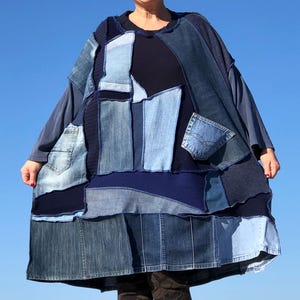 Pode incluir: Um vestido comprido de ganga azul com patchwork, com um painel de malha azul marinho. O vestido tem um caimento solto e um decote redondo.