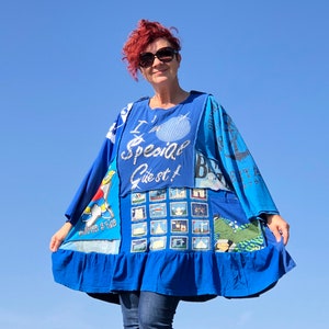 Op de afbeelding: Een blauwe patchworkjurk met een geruite zoom. De jurk heeft verschillende bedrukte ontwerpen, waaronder een afbeelding van een cartoonfiguur, een fotocollage en de tekst "I am a Special Guest!"