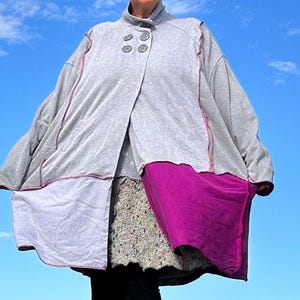 May include: An oversized cardigan in grey and pink with a button fastening. The cardigan is made from a soft, comfortable fabric and has a relaxed fit.