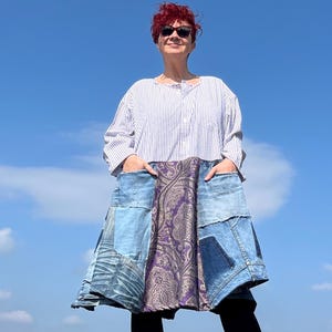 Puede incluir: Una mujer con una camisa a rayas azules y blancas con una falda vaquera hecha de diferentes piezas de mezclilla y una tela paisley morada.