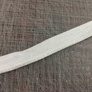 May include: A white, woven fabric ribbon with a slightly textured surface.